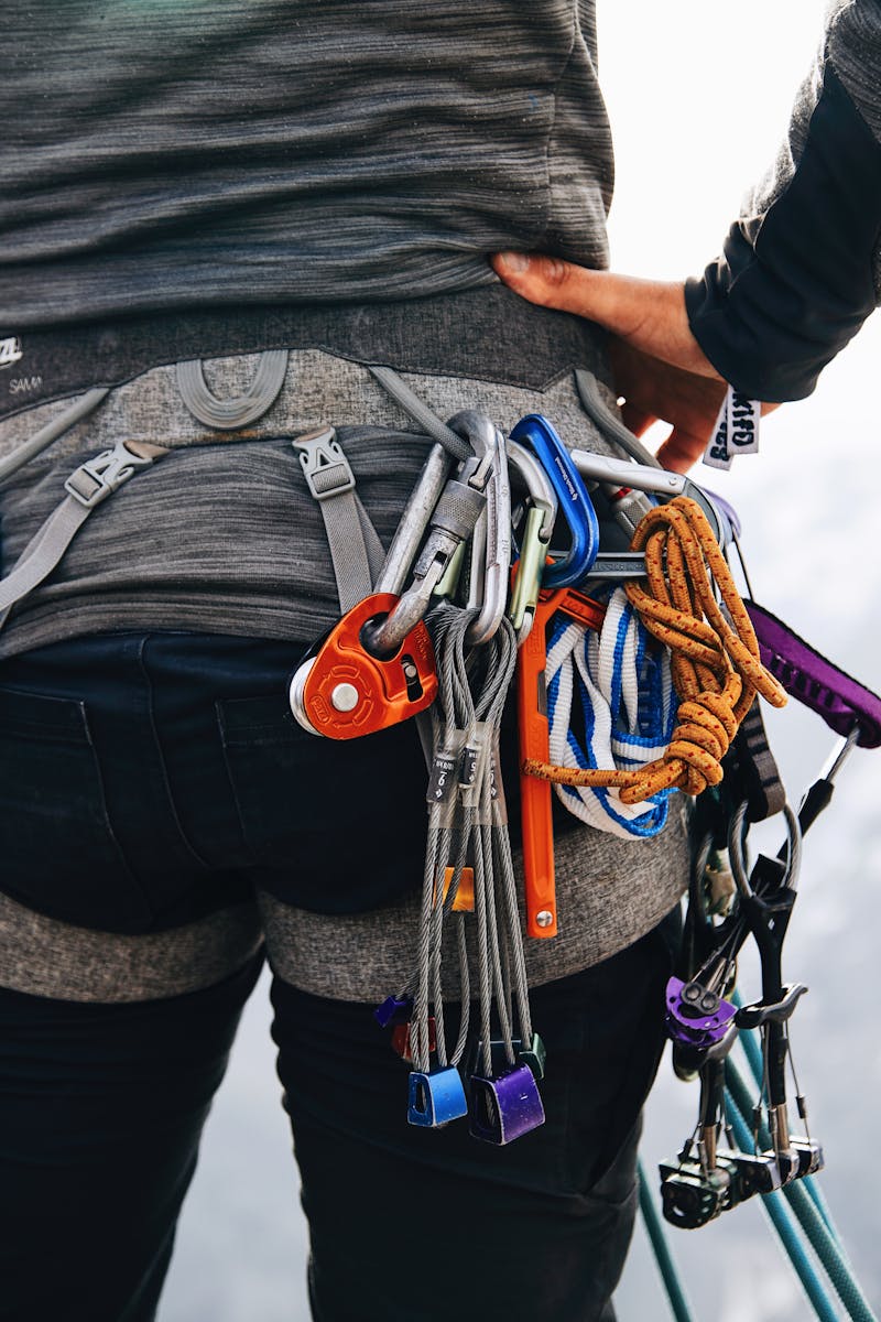 A climber stands with gear in snowy mountains, showcasing adventure and preparedness.